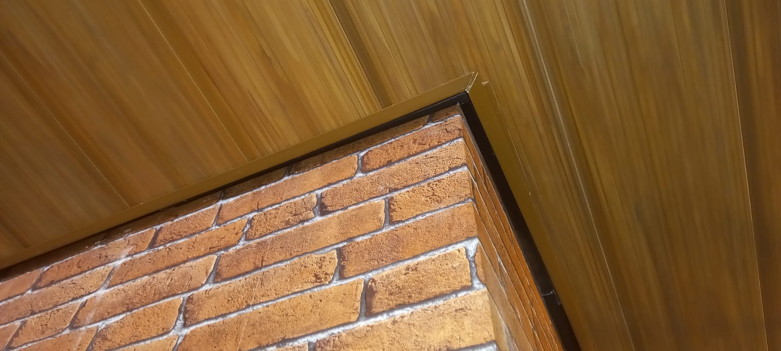 Acabamento de forro madeirado no encontro com parede de tijolinho
